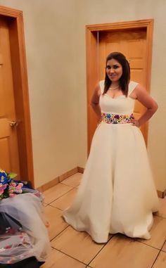 a woman in a white dress standing next to two doors with flowers on the floor