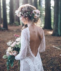 the back of a woman's dress with flowers in her hair, holding a bouquet