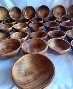 many wooden bowls are lined up on a white tablecloth and laid out in rows