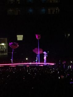 a person standing on top of a stage in the middle of a dark room with lights