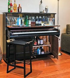 a piano sitting in the middle of a living room next to a bar with liquor bottles on it