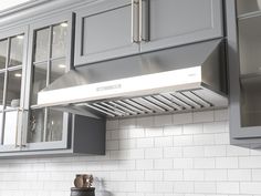 a kitchen with gray cabinets and stainless steel range hood