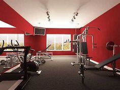 an empty gym room with red walls and black carpeted flooring is seen in this image