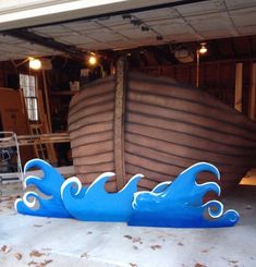 a large wooden boat sitting on top of a garage floor next to a pile of leaves