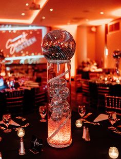 a disco ball is sitting on top of a tall glass vase filled with crystal balls