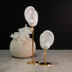 two white vases sitting on top of a table next to each other with flowers in them