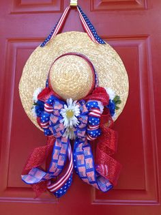 a straw hat with red, white and blue ribbons hanging on a door handle that is decorated with an american flag bow