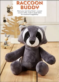 a raccoon stuffed animal sitting on top of a wooden floor