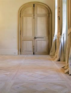 an empty room with wooden doors and curtains