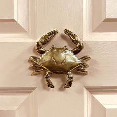 a gold crab door knocker on a white door