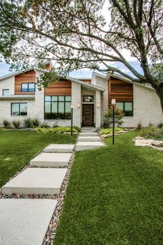 a white house with stone steps leading to the front door and grass area in front