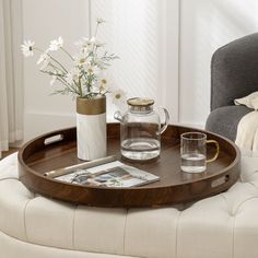 a wooden tray with flowers on top of it next to a glass pitcher and cup