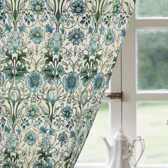 the curtains are hanging on the window sill in front of the vase with flowers