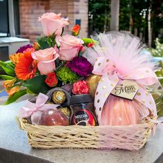 a basket filled with lots of different types of food and flowers on top of a table