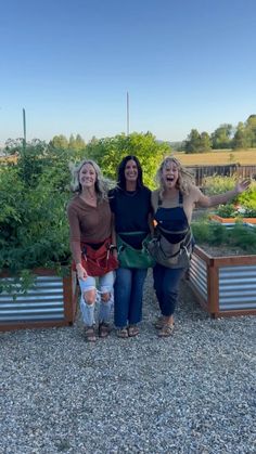 three women standing next to each other in a garden