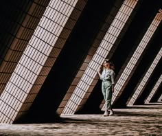 a woman is walking down the street in front of some tall buildings and talking on her cell phone