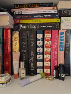 a shelf filled with books and cosmetics on top of a white counter next to other items