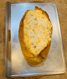 a baked potato sitting on top of a metal pan covered in cheesy cheese