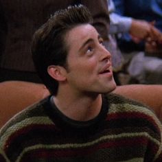 the young man is looking up while wearing a striped sweater and black pants with his eyes wide open