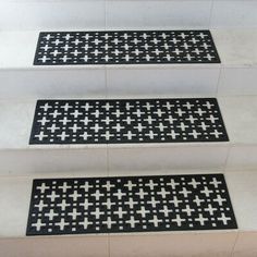 three black and white stair mats on the side of some steps with crosses in them