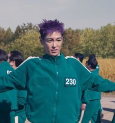 a group of young men standing next to each other wearing green jackets and purple hair