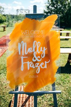 a welcome sign for the newly married couple on an easel in front of a picnic table