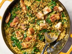 a skillet filled with chicken and rice covered in greens