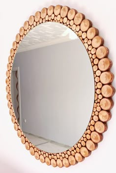 a mirror made out of wooden logs on the wall next to a white wall with a door