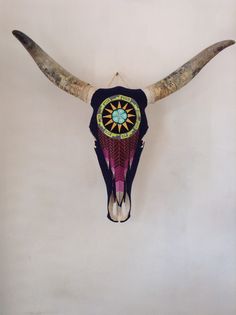 a bull's head with long horns and a colorful design on it is hanging from the wall