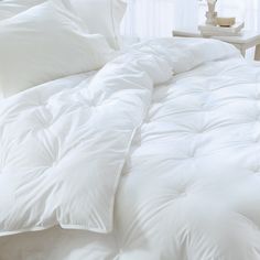 a bed with white comforters and pillows on it