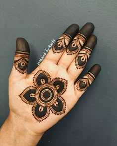 a hand with henna tattoos on it and an intricate flower design in the middle