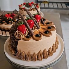 two cakes sitting on top of a table covered in frosting and toppings with strawberries