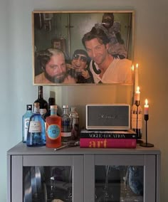 a shelf with bottles, candles and pictures on it