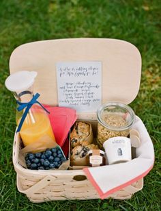 a picnic basket filled with food and drinks on top of a grass covered park area