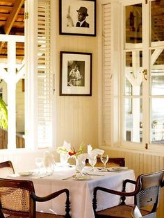 a dining room table with two chairs and pictures on the wall above it, along with wine glasses