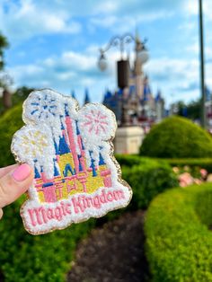 someone is holding up a disneyland mouse shaped cookie in front of the castle at magic kingdom