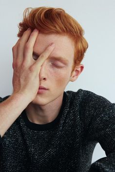 a man with red hair holding his hands to his face