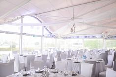 tables and chairs are set up in a tented area for a formal function with white linens