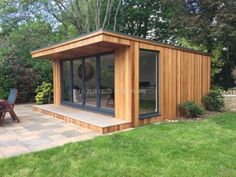 a small wooden building sitting on top of a lush green field next to a picnic table