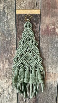 a crocheted christmas tree hanging on a wooden wall with fringes and beads