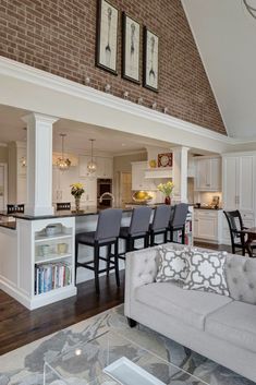 a living room filled with furniture next to a kitchen and dining room table in front of a brick wall