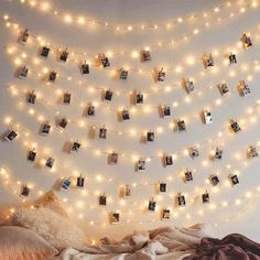 a bedroom with lights strung from the ceiling and pictures on the wall above the bed