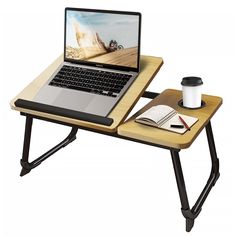 a laptop computer sitting on top of a wooden desk next to a cup of coffee