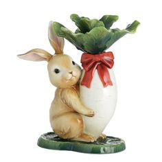 a figurine of a bunny hugging an egg with a red bow around its neck