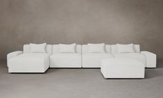 a large white couch with pillows on it in front of a gray wall and floor