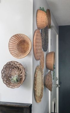 woven baskets hang on the wall above a fireplace