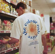 a man in a white t - shirt is looking at the food on the shelf