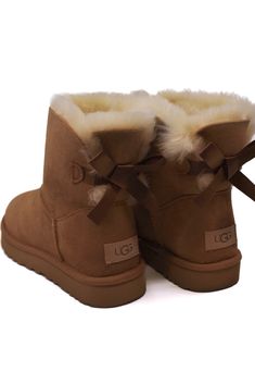 Experience a touch of elegance with our iconic UGG® Mini Bailey Bow II Chestnut, now adorned with silky bows for a charming and feminine touch. Made with luxurious sheepskin, this versatile boot boasts a durable yet lightweight sole for added comfort and grip. A staple for any fashionista's wardrobe, this boot is sure to be a fan favorite!

This product was made in a factory that supports women in our supply chain with the help of HERproject, a collaborative initiative that creates partnerships with brands like ours to empower and educate women in the workplace. Uggs With Bows On The Back, Boots With Bows, Ugg Mini Bailey Bow, Bow Uggs, Ugg Boots With Bows, Ugg Bailey Boots, Uggs With Bows, Women In The Workplace, Mini Baileys