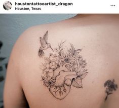 a heart tattoo with flowers and a bird on the back of someone's shoulder