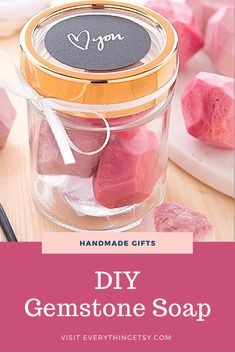 a jar filled with pink and yellow soaps on top of a wooden table